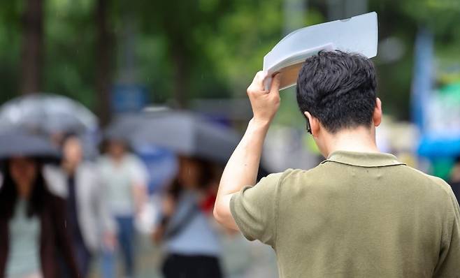 소나기가 내린 30일 서울 여의도에서 우산을 챙기지 못한 시민이 비닐 파일로 머리를 가린 채 발걸음을 재촉하고 있다.    뉴스1