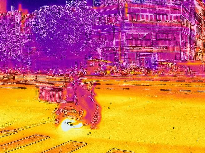 폭염경보가 내려진 지난달 3일 서울 동대문 종합시장 인근에서 배달 노동자가 아스팔트 열기를 받으며 신호를 기다리고 있다. 열화상 카메라는 높은 온도는 붉게, 낮은 온도는 파랗게 보인다. 조태형 기자