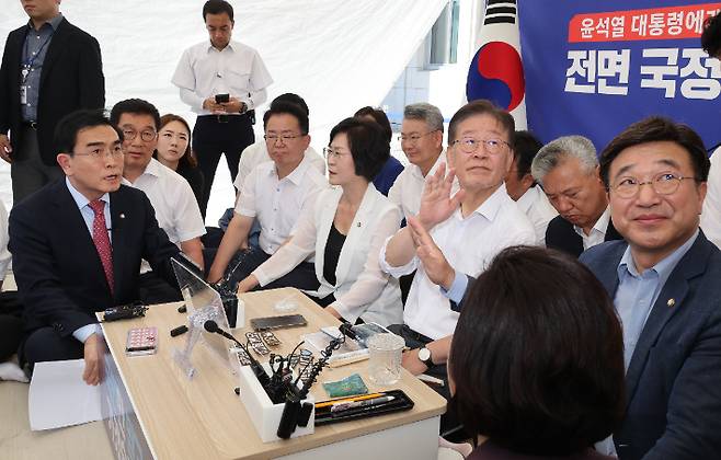 더불어민주당 이재명 대표가 단식 투쟁 중인 국회 앞 천막에서 국민의힘 태영호 의원을 만나고 있다. 이 대표가 퇴장을 요구하는 당직자들에게 그만하라는 손짓을 하고 있다. 태 의원은 본회의장 야당 의원들의 발언에 항의하기 위해 이재명 대표를 찾았다. 연합뉴스