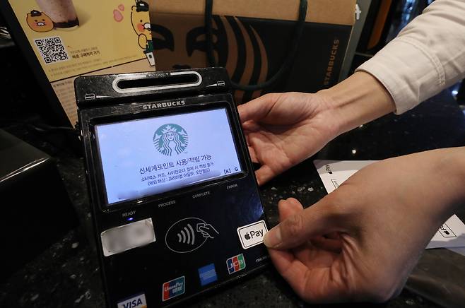 서울 시내 한 스타벅스 매장에서 관계자가 애플페이 가능 스티커를 NFC 단말기에 부착하고 있다. /뉴스1