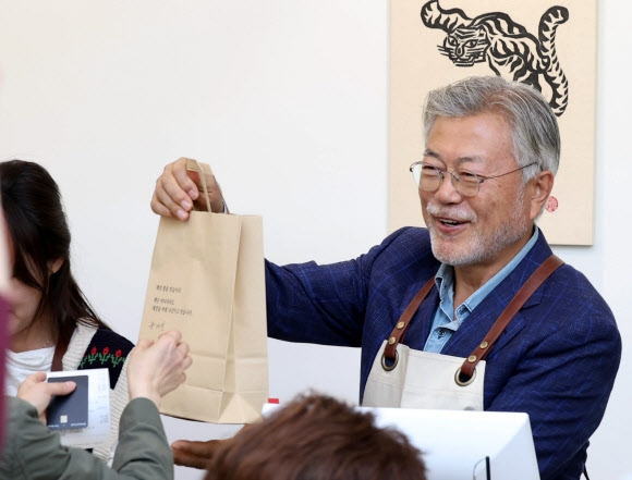 문재인 전 대통령이 경남 양산시 하북면 자신의 책방 ‘평산책방’에서 계산 업무를 하며 책을 손님에게 건네고 있다. 2023.4.26 연합뉴스