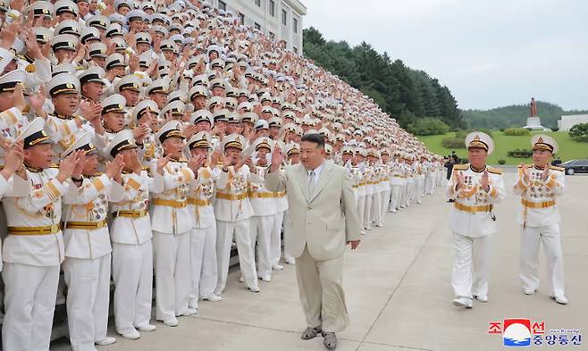 김정은 북한 국무위원장이 지난달 28일 북한 해군절 행사에 참석해 군인들을 향해 손을 흔들고 있다. 크림색 양복에 회색 샌들을 깔 맞춤 한 복장이 피셔맨 샌들 유행 시기와 맞아 들어 외신들의 주목을 받았다. [조선중앙통신]
