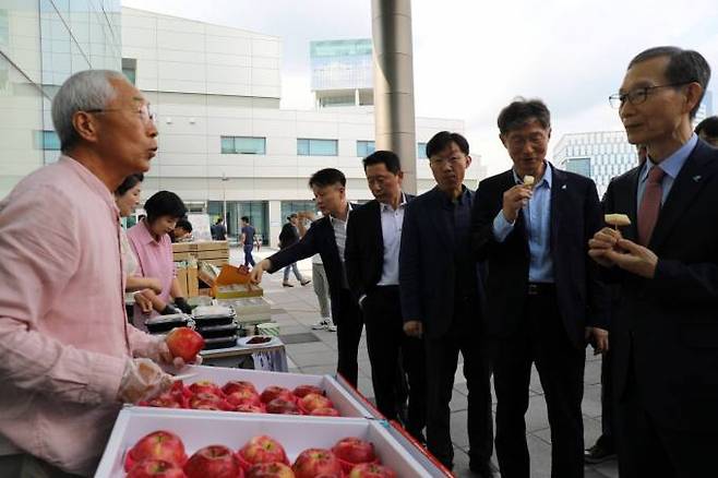 11일 한국광해광업공단 야외공간에 마련된 직거래 장터에서 황규연 사장이 지역 사회적경제기업 대표가 판매하는 사과를 시식하며 이야기를 나누고 있다. 한국광해광업공단