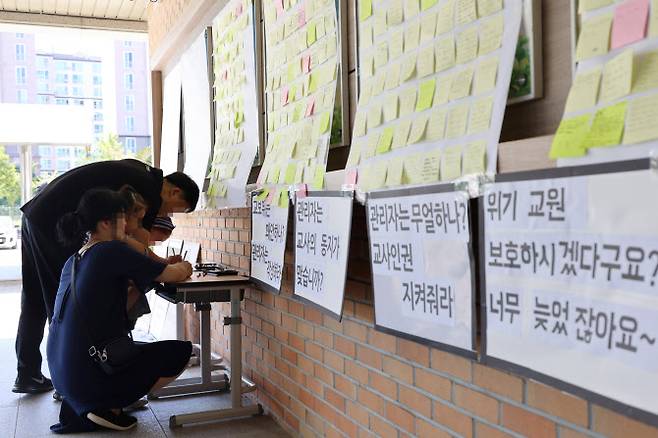 악성 민원에 시달리다 세상을 떠난 대전 초등 교사가 재직하던 유성구 한 초등학교에 마련된 추모공간에 지난 9일 오후 한 학부모가 고인을 추모하는 쪽지를 작성하고 있다 (사진=연합뉴스)