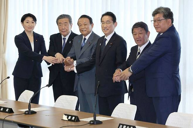 기시다 후미오(오른쪽에서 세번째) 일본 총리가 13일 도쿄 지요다구에 있는 자민당 당사에서 새로운 당 간부들과 손을 잡고 있다. 기시다 총리는 이날 당 인사와 대대적인 개각을 단행했다. 도쿄/AFP 연합뉴스