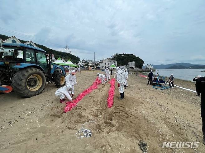 [통영=뉴시스] 신정철 기자= 통영해양경찰서는 13일 오염사고 발생 시 체계적이고 신속한 해안방제를 위해 통영시 도남동 수륙해수욕장애서 ‘23년 민·관 합동 해안방제훈련을 실시했다. 사진은 17개의 기관·업체 등 참가자들이 해안모래를 파고 중질유 부착제를 설치하고 있다.(사진=통영해경 제공).2023.09.13. photo@newsis.com *재판매 및 DB 금지