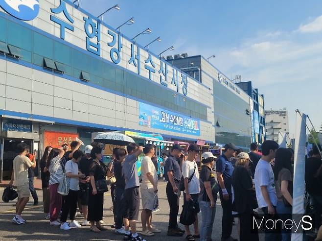 지난 9일 '강서 수산시장 수산대축제'에서 할인 쿠폰을 받기 위해 줄을 선 시민들. 내리쬐는 햇빛이 뜨거워 양산이나 손, 모자로 얼굴을 가리고 있다. /사진=김지연 기자