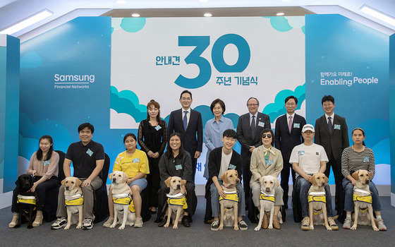 From left behind, Rep. Kim Ye-ji of the People Power Party, Samsung Electronics Chairman Lee Jae-yong, late Samsung chairman's wife Hong Ra-hee, International Guide Dog Federation Chairman William Thornton, Samsung Fire & Marine Insurance CEO Hong Won-hak and Samsung Guide Dog School director Park Tae-jin pose for the photo with guide dogs and their new partners at the ceremony to celebrate 30 years since the school's establishment in Yongin, Gyeonggi, on Tuesday. [SAMSUNG]