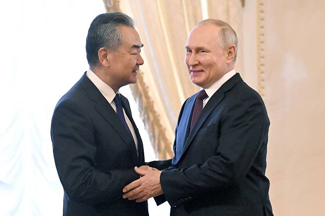 블라디미르 푸틴(오른쪽) 러시아 대통령이 20일(현지 시각) 상트페테르부르크에서 왕이 중국 공산당 중앙정치국 위원 겸 외교부장(장관)과 손을 맞잡고 있다. /타스 연합뉴스