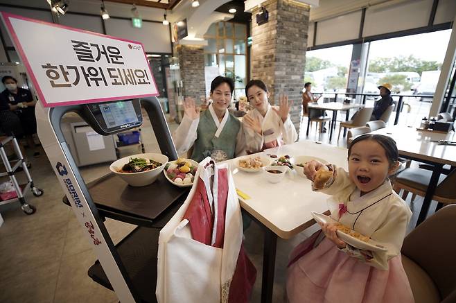 LG유플러스가 추석을 앞두고 21일 경부고속도로 천안삼거리휴게소(상행)에서 한복 차림의 'U+서빙 로봇'을 선보였다. 천안삼거리휴게소는 지난 6월부터 서빙 로봇을 운영해 메뉴 주문과 서빙부터 퇴식까지 전 과정을 무인화했다. 사진은 추석을 맞아 한복을 입은 LG유플러스 모델과 'U+ 서빙 로봇' 모습. LG유플러스