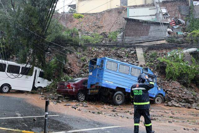 7월 필리핀 북부 바기오의 주택가에서 경찰관이 태풍 독수리로 인한 토사로 파손된 차량을 점검하고 있다. 필리핀 북부를 강타한 제5호 태풍 독수리의 여파로 저지대 마을에서 홍수가 발생하고 정전 등이 빚어졌으며 1만2,000여 명의 이재민이 발생했다. 바기오=AP 뉴시스