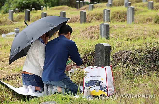 '조금 빨리 왔어요' 차례 지내는 부부 추석 연휴를 일주일 앞둔 지난 21일 광주 북구 망월공원묘지에서 한 가족이 성묘하고 있다. [연합뉴스 자료 사진]