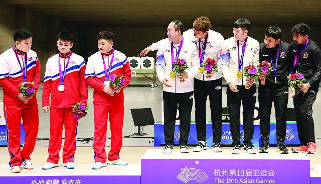 항저우아시안게임 사격 남자 10ｍ 러닝타깃 단체전에서 북한을 꺾고 금메달을 목에 건 하광철, 정유진, 곽용빈이 25일 중국 항저우 푸양 인후 스포츠센터에서 열린 시상식에서 은메달을 딴 북한 선수들에게 함께 기념촬영할 것을 요청하고 있다. 침울한 표정의 북한 선수들은 이를 거절했다. 동메달을 차지한 인도네시아 선수들이 이런 모습에 의아한 표정을 짓고 있다. 연합뉴스