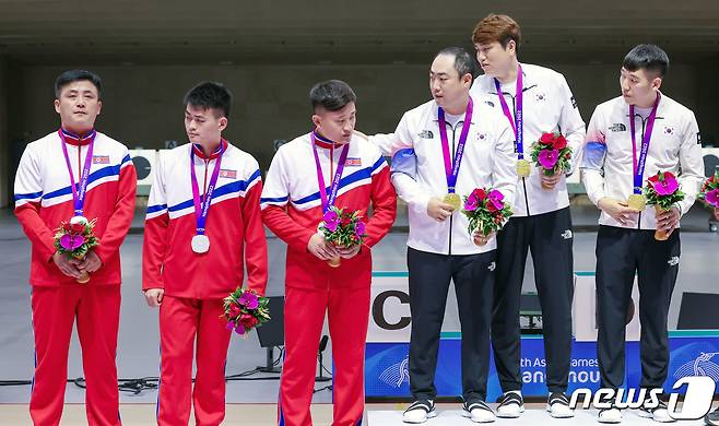25일 오후 중국 항저우 푸양 인후 스포츠센터에서 열린 2022 항저우 아시안게임 남자 10m 러닝타깃 단체전에서 1위를 차지한 대한민국 하광철(왼쪽부터)과 정유진, 곽용빈이 기념촬영을 앞두고 북한 선수단에 1위 단상에 나란히 설 것을 권하고 있다. 우리 선수단 왼쪽은 2위를 차지한 북한 박명원(왼쪽부터), 유송준, 권광일. 2023.9.25/뉴스1 ⓒ News1 민경석 기자