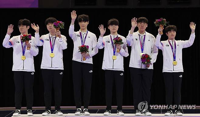 영광의 주인공들 (항저우=연합뉴스) 신현우 기자 = 29일 중국 저장성 항저우 e스포츠 센터에서 열린 제19회 항저우 아시안게임 e스포츠 리그 오브 레전드(LoL)에서 금메달을 딴 한국 선수들이 시상대에 올라 손을 흔들고 있다. 왼쪽부터 '제우스' 최우제, '카나비' 서진혁, '쵸비' 정지훈, '페이커' 이상혁, '룰러' 박재혁, '케리아' 류민석. 2023.9.29 nowwego@yna.co.kr