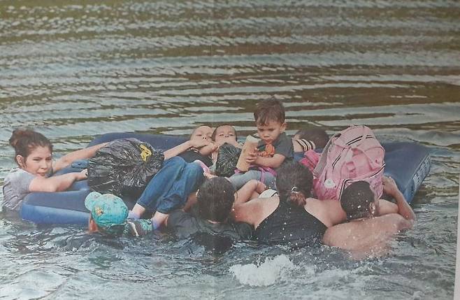지난 5월11일 이주자 가족이 에어매트에 어린이들을 태우고 미국과 멕시코 국경의 리오그란데 강을 건너고 있다.  [사진 =AFP연합뉴스]