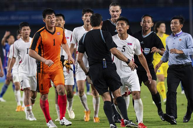 북한 남자축구 대표팀이 항저우 아시안게임 8강전에서 일본에 패한 뒤 주심에게 거칠게 항의하고 있다. 사진=AP PHOTO