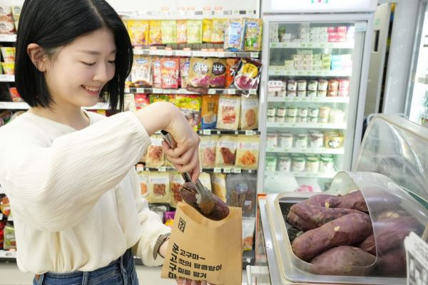 모델이 세븐일레븐에서 동절기 상품인 군고구마를 봉투에 담고 있다[사진제공=세븐일레븐].