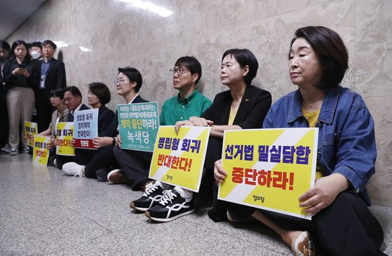 노동당·녹색당·정의당·진보당 의원 및 당원들이 지난달 14일 오전 서울 여의도 국회에서 열린 더불어민주당 의원총회 회의장 앞을 찾아 '병립형 비례대표제' 회귀를 규탄하는 피켓 시위를 펼치고 있다. 뉴스1