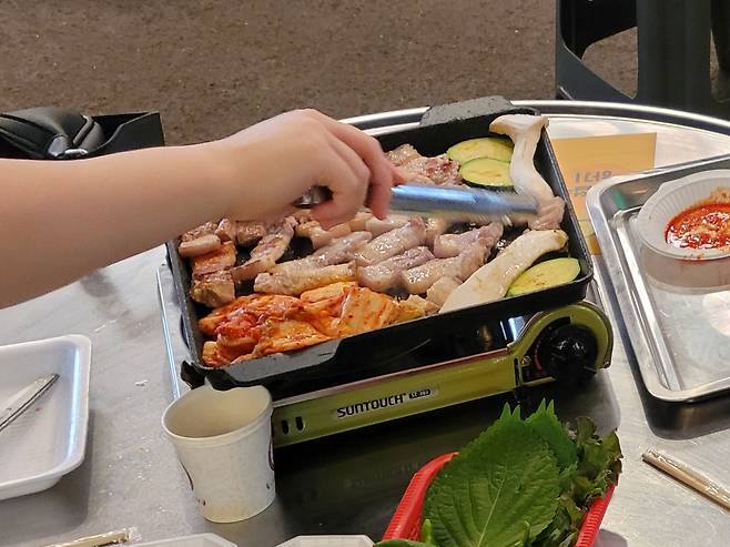 충남 예산시장 장터 광장에서 지난달 25일 시민들이 집게를 빠르게 움직이며 고기를 굽고 있다. /홍다영 기자
