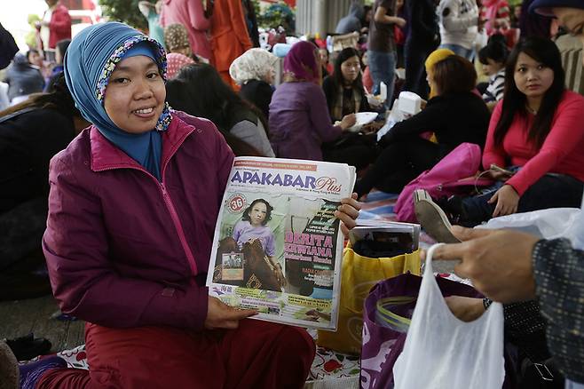 2014년 1월 홍콩 코즈웨이 베이에서 한 인도네시아 가사노동자가 가사노동자의 학대 사실을 보도한 신문을 들어보이고 있다. 게티이미지