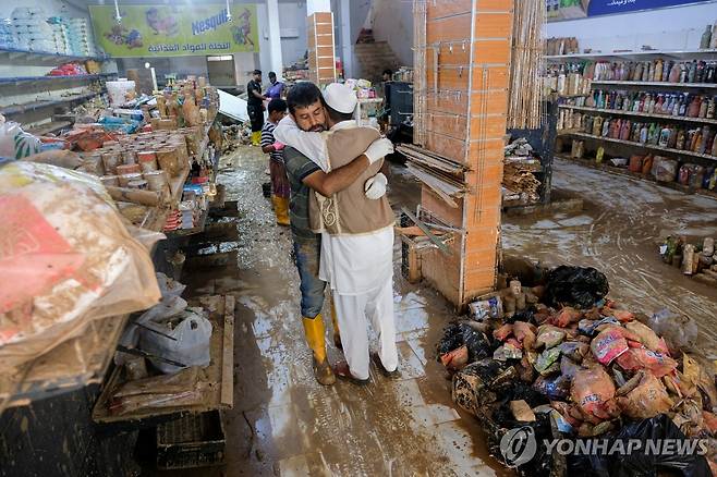 대홍수로 폐허가 된 리비아 데르나의 한 식료품점에서 서로를 끌어안고 있는 주민들. [로이터 연합뉴스 자료사진. 재판매 및 DB 금지]