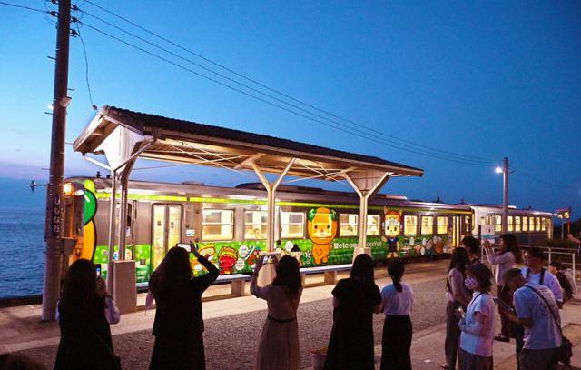 시모나다역에 기차가 도착하자 여행객이 일제히 휴대전화로 사진을 찍고 있다.