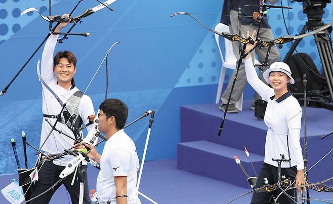 한국 양궁 리커브 국가대표 이우석(맨 왼쪽)과 임시현(맨 오른쪽)이 4일 항저우 아시안게임 혼성 단체전 금메달을 합작한 후 활짝 웃으며 활을 들어 올리고 있다. 한국은 결승에서 일본을 6대0으로 완파하고 이번 대회 양궁 첫 금메달을 따냈다. /뉴스1