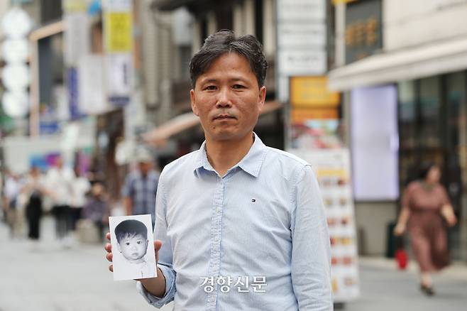 어릴 적 부모와 헤어진 후 시설에서 자란 조민호씨(49)가 지난달 12일 서울 종로구 한 카페에서 경향신문과 인터뷰하던 도중 본인의 어릴 적 사진을 보여주고 있다. 한수빈 기자