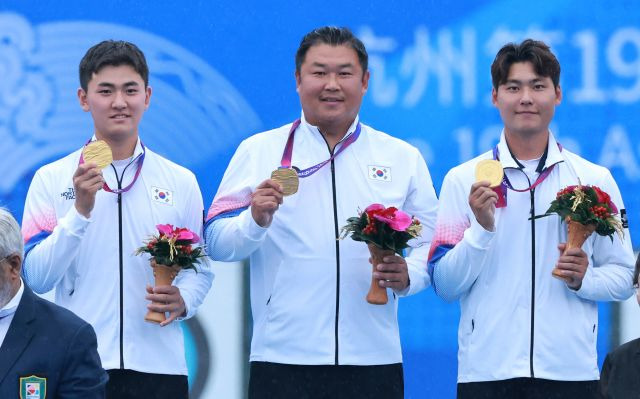 한국 남자양궁 대표팀 김제덕, 이우석, 오진혁 선수가 6일 2022 항저우 아시안게임 양궁 리커브 남자 단체전 결승에서 인도를 꺾고 금메달을 받은 뒤 기뻐하고 있다. 연합뉴스