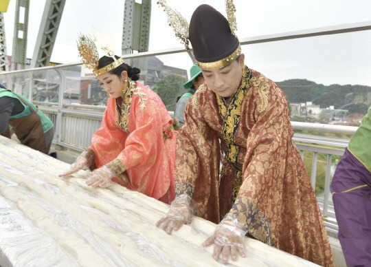 '2023 대백제전' 세부 프로그램으로 7일 충남 공주시 금강철교 위에서 열린 '인절미 축제'에서 무령왕과 왕비로 선발된 시민이 인절미를 만들고 있다. 공주시는 이 축제에서 '단일 장소에서 동시에 만들어진 가장 긴 인절미' 부문 한국기록원 공식 최고 기록을 수립했다고 밝혔다. 사진=공주시 제공