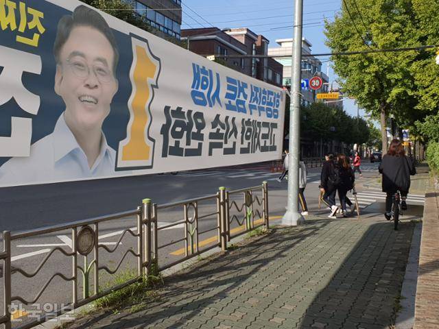 6일 오전 서울 강서구 한 초등학교 인근에 있는 어린이보호구역 옆 펜스 위에 정당현수막이 설치돼 있다. '2m 이상 높이 설치' 규정을 위반한 현수막 옆으로 아이들이 길을 건너고 있다. 박시몬 기자