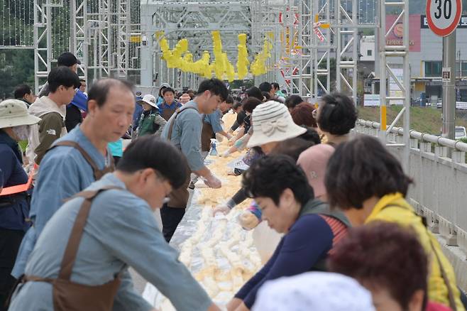 지난 7일 충남 공주시 금강철교 위에서 열린 인절미 축제에서 시민들이 국내에서 가장 긴 인절미 만들기 행사에 참여하고 있다. /연합뉴스