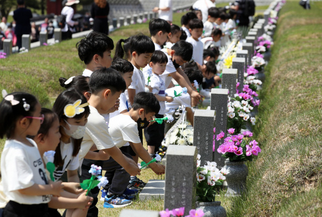 지난 5월 16일 광주 북 구 운정동 국립 5·18민주묘지에서 아이들이 헌화하고 있다. 광주=연합뉴스