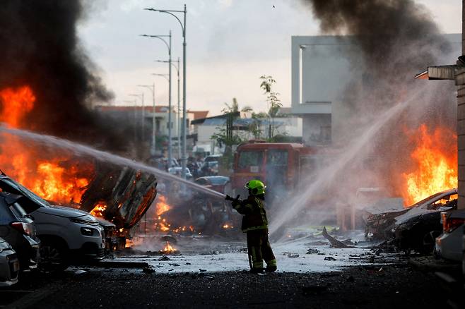 FILE PHOTO: An emergency personnel works to extinguish the fire after rockets are launched from the Gaza Strip, as seen from the city of Ashkelon, Israel October 7, 2023. REUTERS/Amir Cohen/File Photo