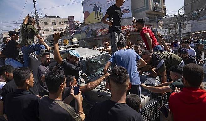 7일(현지시간) 팔레스타인 무장테러 단체 하마스가 끌고온 이스라엘 군용 차량 주변에 팔레스타인들이 모여있다. ⓒAP/연합뉴스