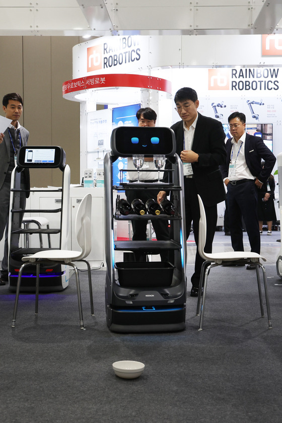 A serving robot moves between chairs at the Robot World 2023 exposition held at Kintex in Goyang, Gyeonggi, on Wednesday. [YONHAP]