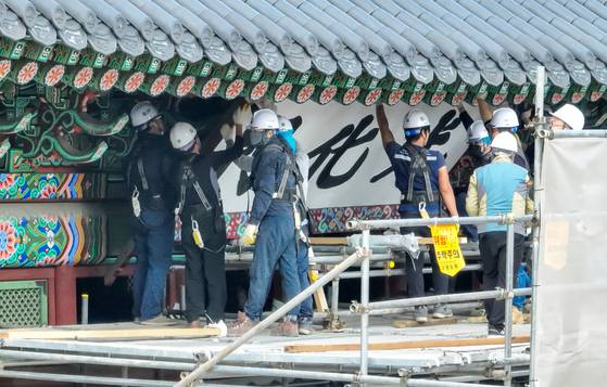 Workers take down the old signboard at Gwanghwamun on Oct. 12. [YONHAP]
