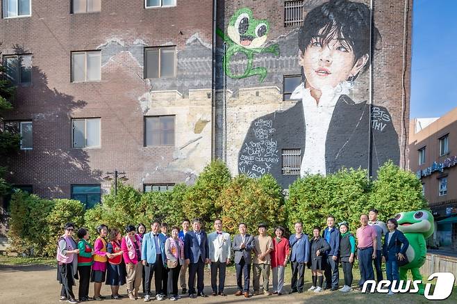 오는 21일 생태교통수원 2013 10주년을 맞아 진행하는 생태교통 수원 뉴페스타 행사를 앞두고 수원화성사업소 벽면에 BTS 뷔의 벽화가 그려져 후원 단체와 시민들이 기념촬영을 하고 있다.(수원시 제공)