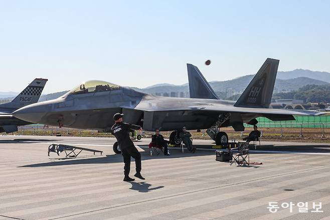 17일 오전 경기도 성남시 서울공항에서 열린 2023 항공우주방위산업전시회(ADEX)에서 F-22가 전시되고 있다. 바로 옆에서 미군 관계자가 미식축구공을 던지며 여유로운 모습이다. 이한결 기자 always@donga.com