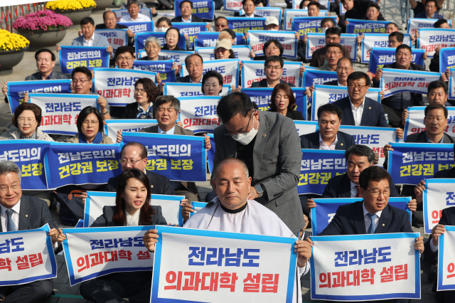 18일 오후 서울 용산 대통령실 앞에서 열린 전라남도 의과대학 신설 촉구대회에서 더불어민주당 김원이 의원이 삭발을 하며 참석자들과 구호를 외치고 있다. 연합뉴스