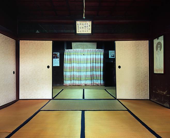 사진작가 오석근의 〈적산 부산(釜山) 03〉. 부산 강서구 대저동에 위치한 일식 주택의 사진으로, 여전히 후스마(襖)와 다다미를 사용하고 있으며 중앙 상단에 가훈이 적힌 액자, 후면에 70년대 커튼이 놓여있는 것을 볼 수 있다. 남부지방의 적산가옥은 난방을 위해 집을 무리하게 변형한 중부지방의 적산가옥과는 그 변화상이 적다. [오석근 작가 제공]