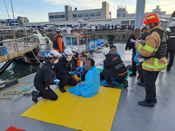 22일 오전 전북 부안군 격포항에서 구급대원들이 전복 사고로 바다에 빠졌다가 구조된 낚싯배 승선원들의 상태를 확인하고 있다. [사진 전북소방본부]