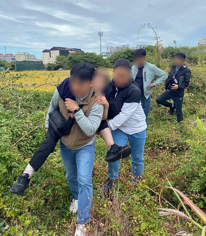 지난 20일 제주시 화북동 한 밭에 쓰러져 있던 피해자를 업고 가는 경찰 [제주동부경찰서 제공. 재판매 및 DB 금지]