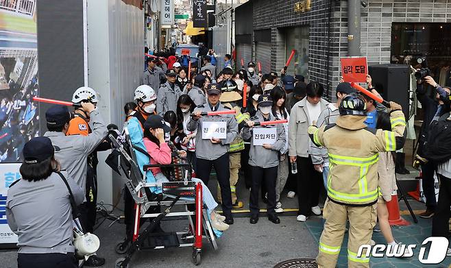 이태원 핼러윈 참사 1주기를 앞둔 25일 서울 광진구 건대맛의거리에서 시민들이 서울시가 새로 도입한 인파감지시스템 활용 유관기관 합동 다중운집 대응 훈련을 하고 있다. 이날 오세훈 서울시장은 이곳을 찾아 주요 인파밀집 지역의 현장 안전관리 계획을 보고받고, 지능형(AI) 폐쇄회로(CC)TV를 활용해 위험 징후를 사전에 알리는 인파감지 시스템을 직접 점검했다. 2023.10.25/뉴스1 ⓒ News1 박지혜 기자