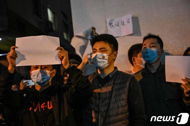 지난해 11월 27일(현지시간) 중국 상하이에서 정부의 고강도 제로 코로나19 봉쇄 정책에 항의하고 우루무치 화재 희생자를 추모하는 주민들이 정부에 항의하는 의미를 담은 ‘백지’를 들고 시진핑 주석의 퇴진을 요구하는 밤샘 시위를 하고 있다.   /AFPBBNews=뉴스1