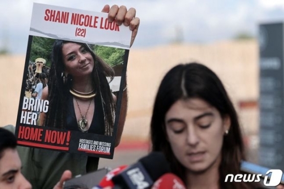 30일(현지시간) 이스라엘 외무부가 성명을 통해 사망을 확인한 독일인 여성 인질 샤니 루크의  사진이 들어간 포스트를 든 채 한 친척이 지난 15일 베냐민 네타냐후 이스라엘 총리와 회담을 마친 후 기자회견을 하고 있다.   AFP 자료사진 뉴스1