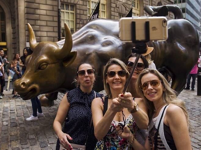 관광객들이 미국 뉴욕 월가에서 강세장의 상징으로 통하는 황소상과 사진을 찍고 있다. /로이터 연합뉴스