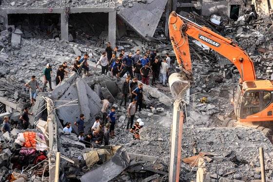 25일(현지시간) 가자지구 남부 칸 유니스에서 이스라엘의 폭격으로 파괴된 건물들 사이에서 생존자와 희생자들의 시신을 수색하는 동안 굴착기가 잔해를 치우고 있다. AFP=연합뉴스
