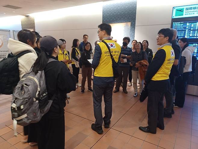 Officials from the South Korean Embassy in Japan greet South Koreans who flew from Israel on a Japanese military plane that landed at Haneda International Airport in Tokyo on Friday evening. (Ministry of Foreign Affairs)